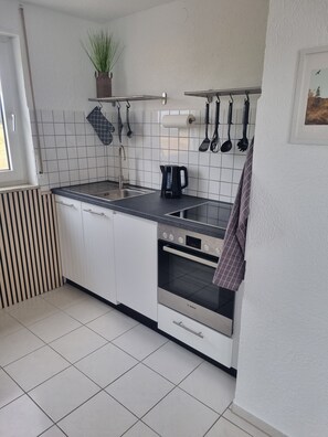 A modern kitchen with white cabinets, a Bosch oven, a sink, and a kettle. - Apartment 'Weitblick' with Mountain View, Balcony, and Wi-Fi (Reute)