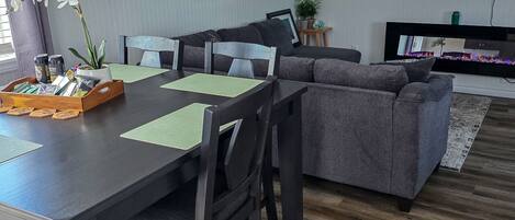 Una sala de estar moderna con una mesa de comedor, sofás y un televisor de pantalla plana.