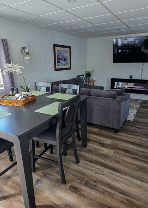 Een moderne woonkamer met een eettafel, banken en een flatscreen televisie.