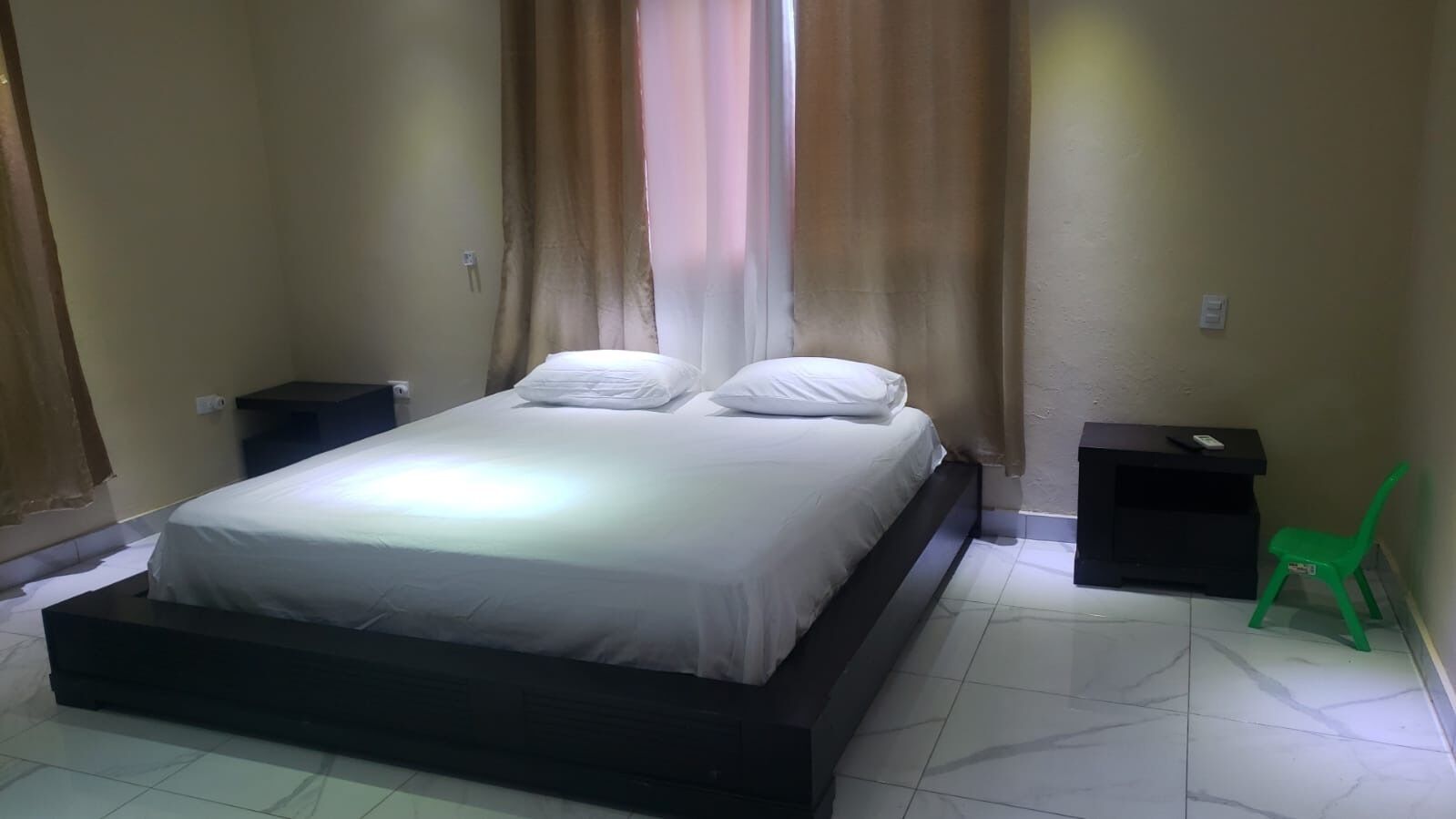 A bedroom with a bed, a nightstand, a desk, and a chair.