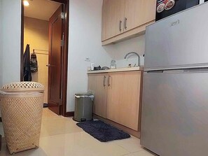 Une cuisine de taille réduite, équipée d’un réfrigérateur, d’un évier et de meubles de rangement en bois.