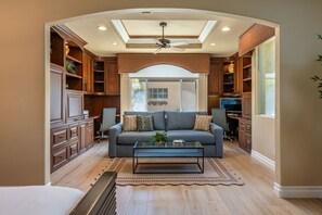 A living room with a sofa, coffee table, and built-in wooden cabinets. - Fairway Peaks at PGA West | Mountain & Golf Views (La Quinta)