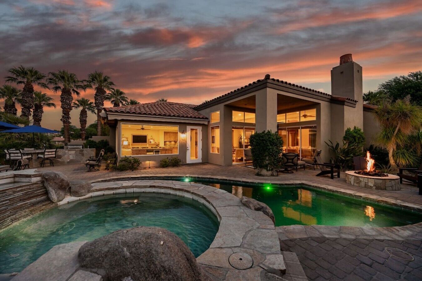 A residential property with a swimming pool, outdoor seating, and a well-lit interior.