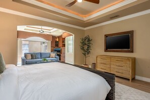 A bedroom with a large bed, a dresser, a television, and a plant. - Fairway Peaks at PGA West | Mountain & Golf Views (La Quinta)