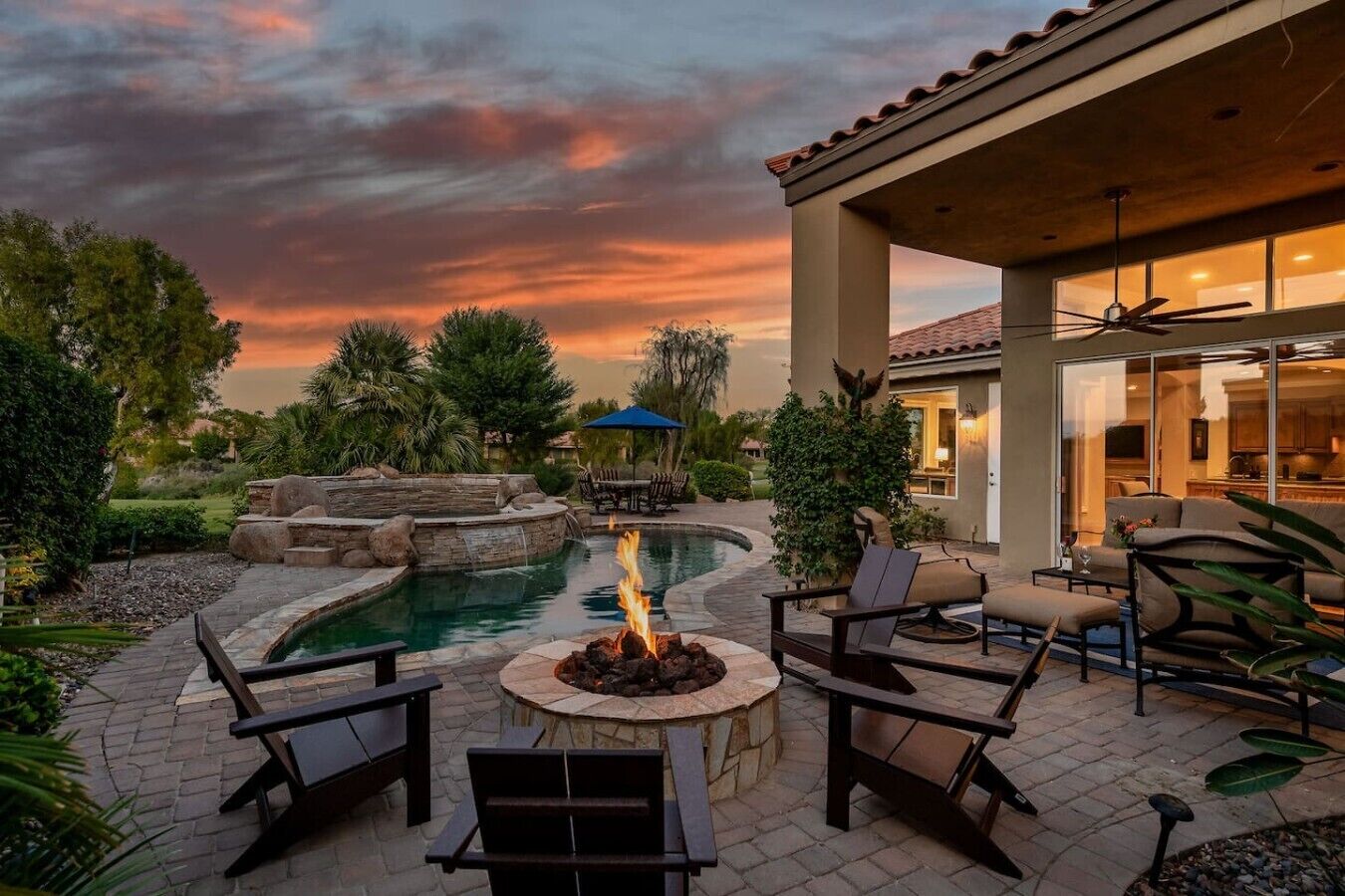 Un patio exterior con piscina, fogata y zona de estar.