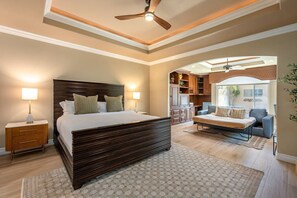 A bedroom with a large bed, bedside lamps, a ceiling fan, and a view of the living area. - Fairway Peaks at PGA West | Mountain & Golf Views (La Quinta)