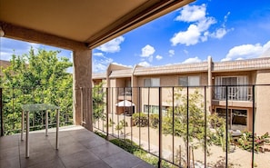 A balcony with a glass table, a view of a building with multiple windows, and a clear sky. - Gorgeous condo in Old Town Scottsdale (Scottsdale)