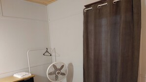 A room with a bed, a white standing fan, a heater, a wardrobe, and a curtain. - Economy Sweet Room No. 5, Double bed, non ac (Saint John)