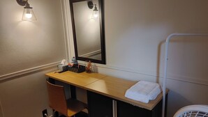 A hotel bathroom with a wooden vanity, a mirror, a towel, and a white fan. - Economy Sweet Room No. 5, Double bed, non ac (Saint John)