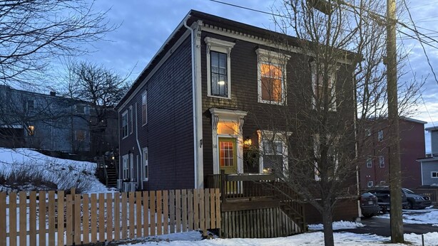 A two-story house with a wooden porch and a picket fence. - Economy Sweet Room No. 5, Double bed, non ac (Saint John)