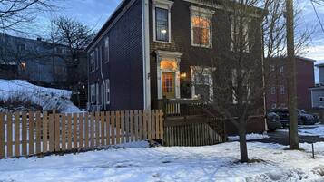 Une maison à deux étages avec une véranda en bois et une clôture faite de piquets.