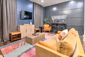 A modern living room with a flat-screen TV, a sofa, a coffee table, and a small side table. - Lux Nash Stay: Private Hot Tub, Rooftop & 12 Beds! (Nashville)
