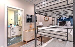 A bunk bed with a metal frame, a bedside table with a lamp, a mirror, and a wall-mounted TV. - Lux Nash Stay: Private Hot Tub, Rooftop & 12 Beds! (Nashville)