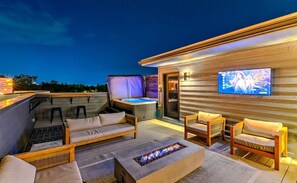 Eine Dachterrasse mit Sitzgelegenheiten im Freien, einem Whirlpool und einem Flachbildfernseher.