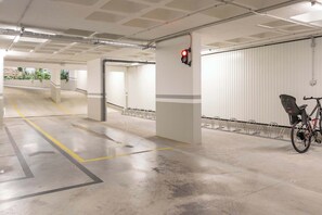 Eine Tiefgarage mit Betonböden, weißen Wänden und einem roten Hinweisschild für den Ausgang.