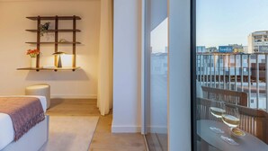A modern hotel room with a balcony, a bedside table with a lamp, and a view of the cityscape. - Sky Pool Luxury by Portugal Active (Barreiro)