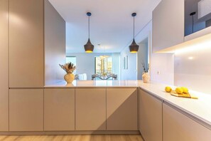 A modern kitchen with a central island, pendant lighting, and a view to a dining area.