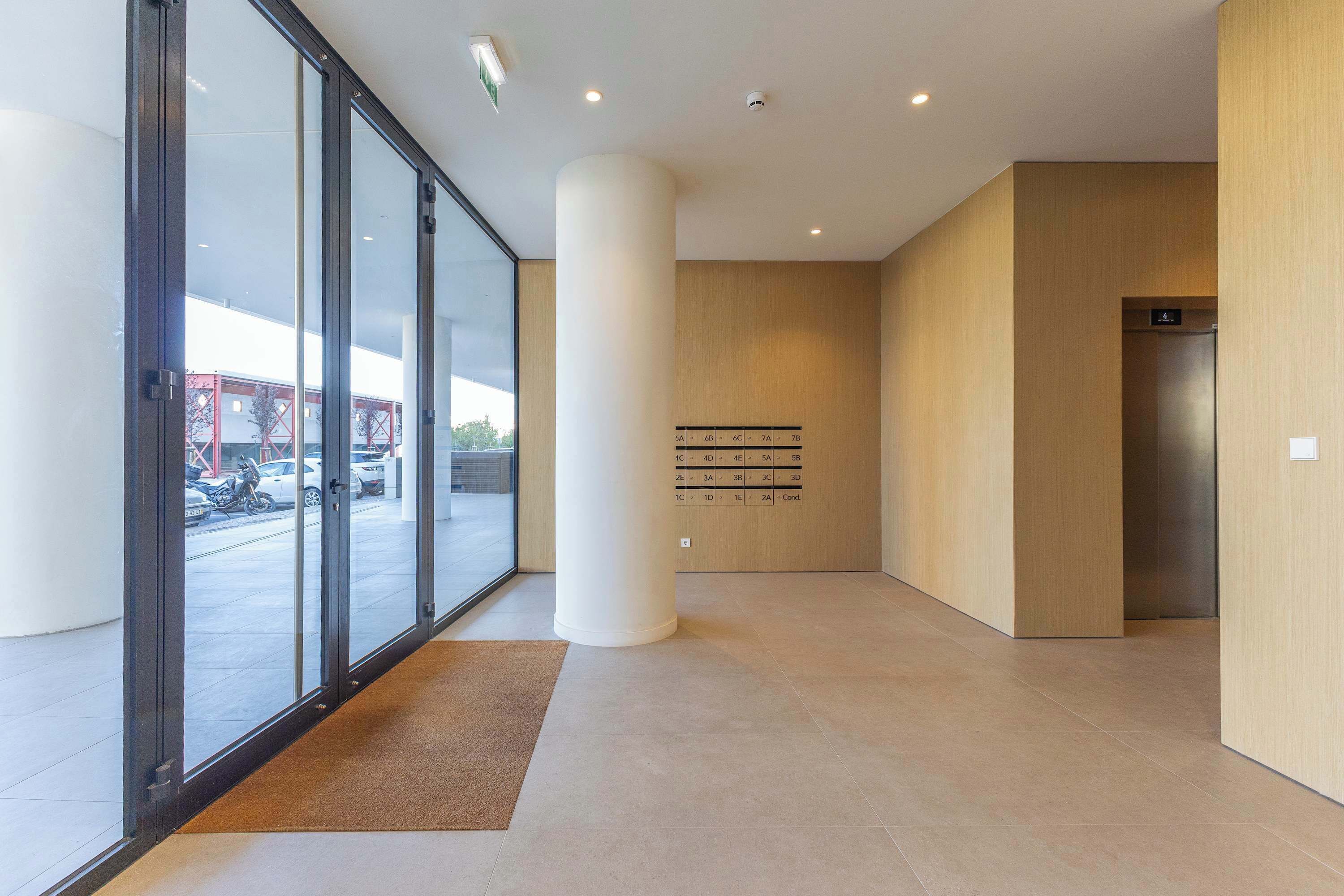 A modern interior with a glass entrance, a central column, and an elevator.