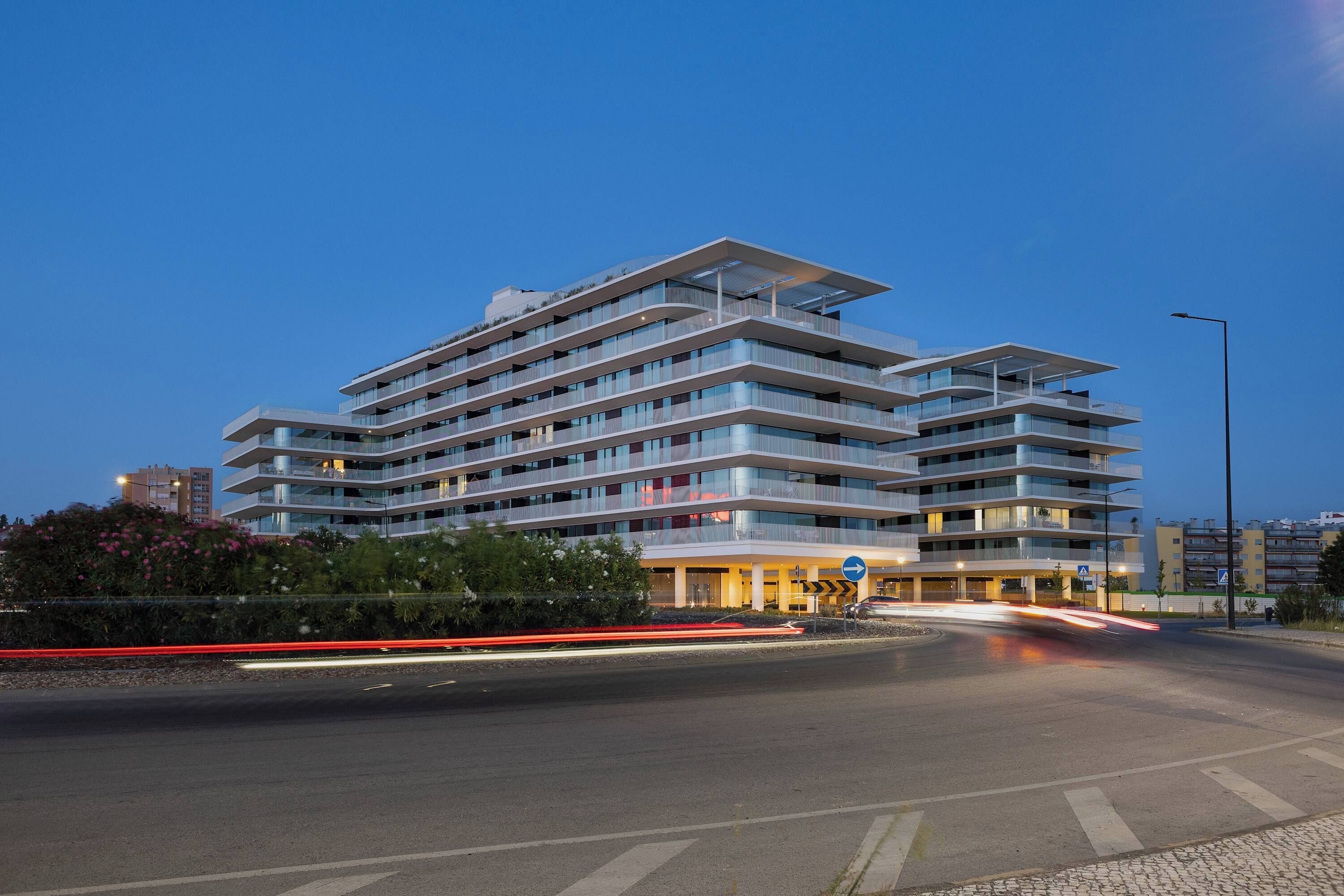 A multi-story hotel with a modern architectural design, featuring balconies and a well-lit entrance.