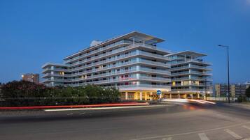A multi-story hotel with a modern architectural design, featuring balconies and a well-lit entrance.