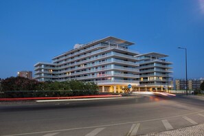 A multi-story hotel with a modern architectural design, featuring balconies and a well-lit entrance.
