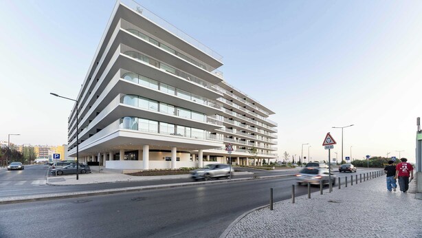 A multi-story hotel with a modern design, featuring balconies on each floor and a parking area in front. - Sky Pool Luxury by Portugal Active (Barreiro)