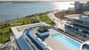 A modern building with a rooftop pool, a view of the sea, and a landscaped area. - Sky Pool Luxury by Portugal Active (Barreiro)