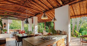 An open-plan kitchen with a large island, dining area, and outdoor seating. - TopSpot con Jacuzzi en el Corazón de Barichara! (Barrio La Loma)