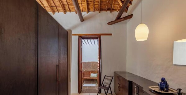 A room with a wooden ceiling, a bench, a chair, a cabinet, and a hanging light fixture. - TopSpot con Jacuzzi en el Corazón de Barichara! (Barrio La Loma)