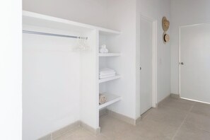 A hallway with a white closet, a door with a hat on the wall, and a tiled floor.