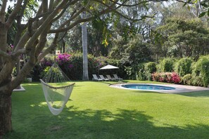Ein Garten mit Pool, einer Hängematte und Liegestühlen.
