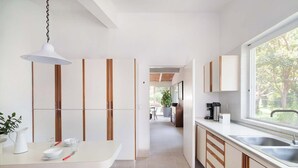 A modern kitchen with a white countertop, wooden cabinets, and a large window.