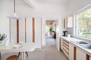 A modern kitchen with a white countertop, wooden cabinets, and a large window.