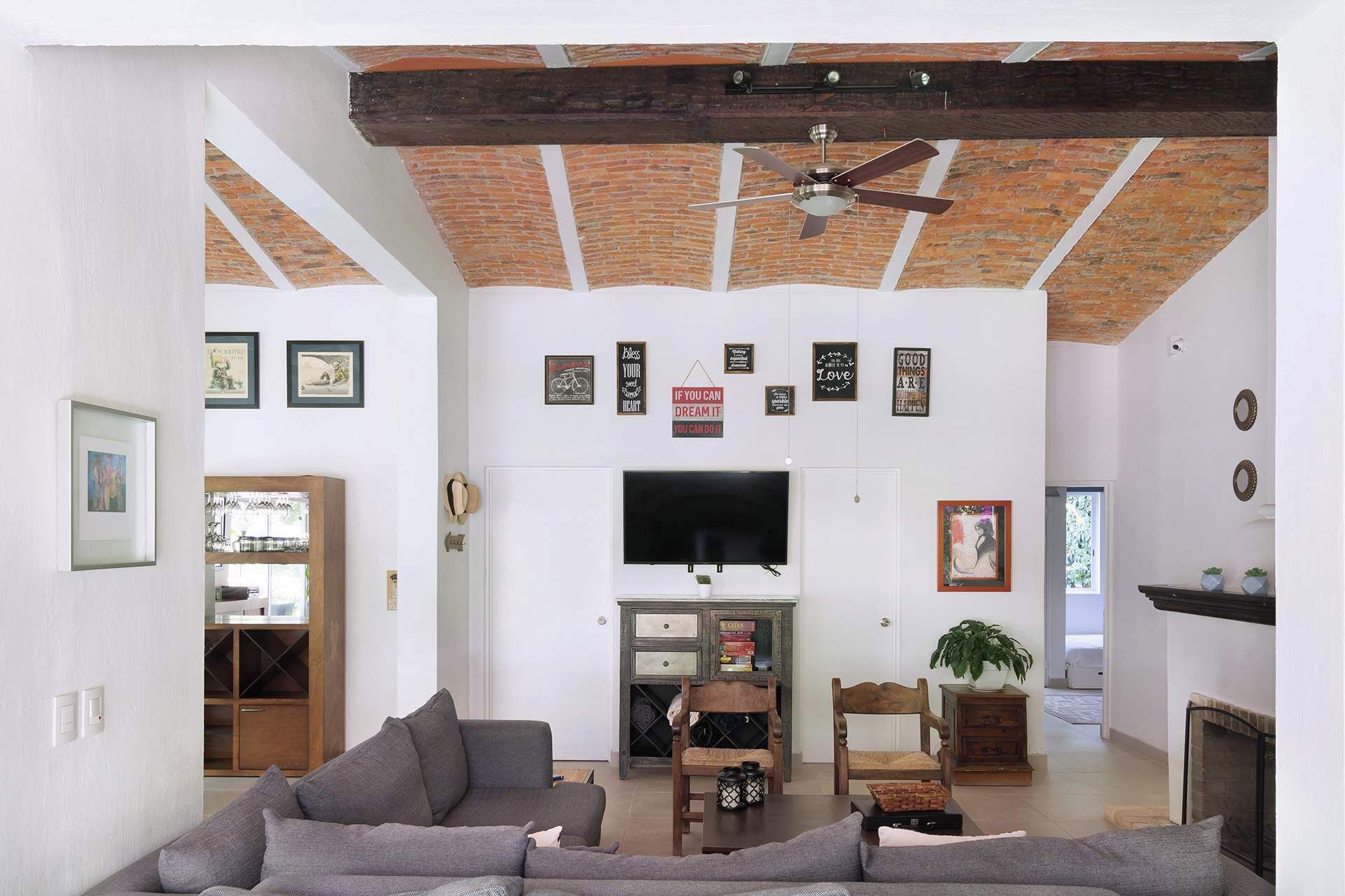 Un salon spacieux doté d’une grande télévision, d’une cheminée et d’un ventilateur de plafond.
