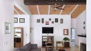 Un salon spacieux doté d’une grande télévision, d’une cheminée et d’un ventilateur de plafond.