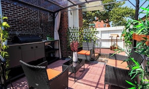 An outdoor patio with a grill, wicker furniture, and potted plants. - Budget Stylish Suite! Kitchenette! Washer! Parking (Queens)
