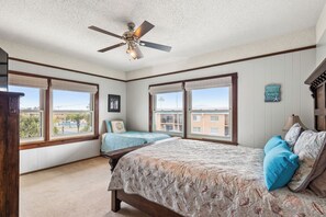 A bedroom with a large bed, two windows, a ceiling fan, and a view of buildings outside. - Luxury Waterfront Retreat - Pool, Hot Tub & Breathtaking Sunsets - Sleeps 12 (St. Augustine)