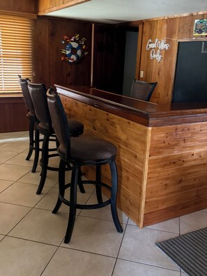 A bar area with wooden paneling, a blackboard with writing, and three black bar stools. - Luxury Waterfront Retreat - Pool, Hot Tub & Breathtaking Sunsets - Sleeps 12 (St. Augustine)