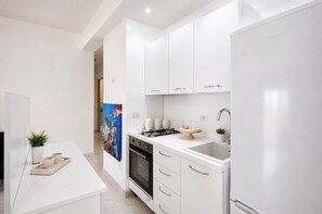 Eine moderne Küche mit weißen Schränken, einem Gasherd, einem Backofen und einem Kühlschrank.