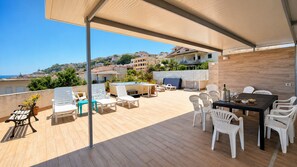 Eine Dachterrasse mit Gartenmöbeln, einem Esstisch und Blick auf die Skyline.
