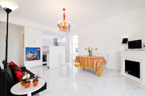 Ein modernes Wohnzimmer mit Essbereich, Kamin und einer Küche im Hintergrund.