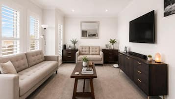 A modern living room with a sofa, a coffee table, a cabinet, and a flat-screen TV.