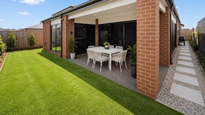 Una propiedad residencial con patio cubierto, césped y fachada de ladrillo.