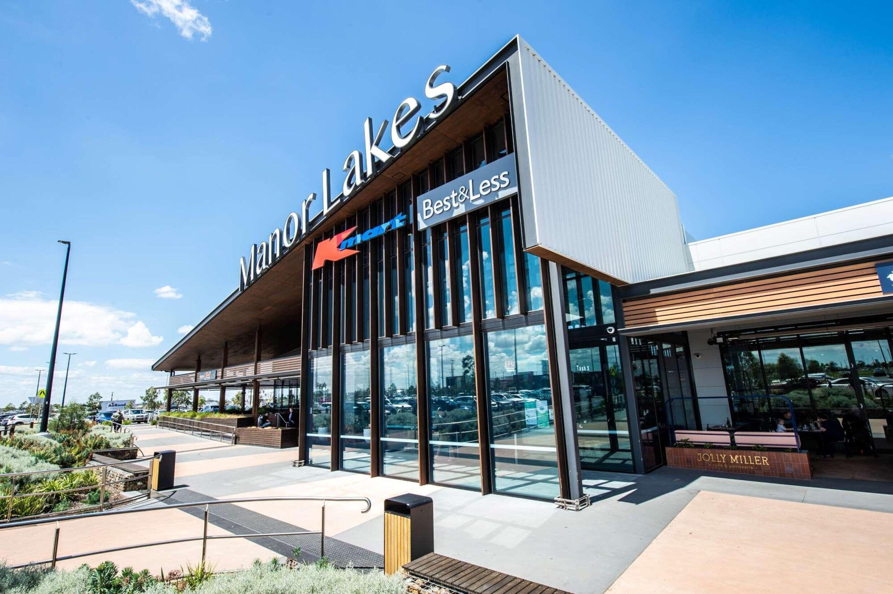 Ein modernes Gebäude mit einer großen Schrifttafel für 'Manor Lakes' und einem 'Best & Less' Geschäft.