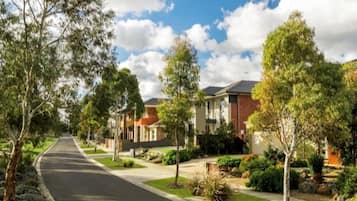 A residential street with houses, trees, and a clear sky.