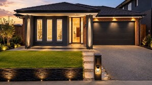 Una casa moderna de dos plantas con fachada oscura, garaje y césped cuidado.