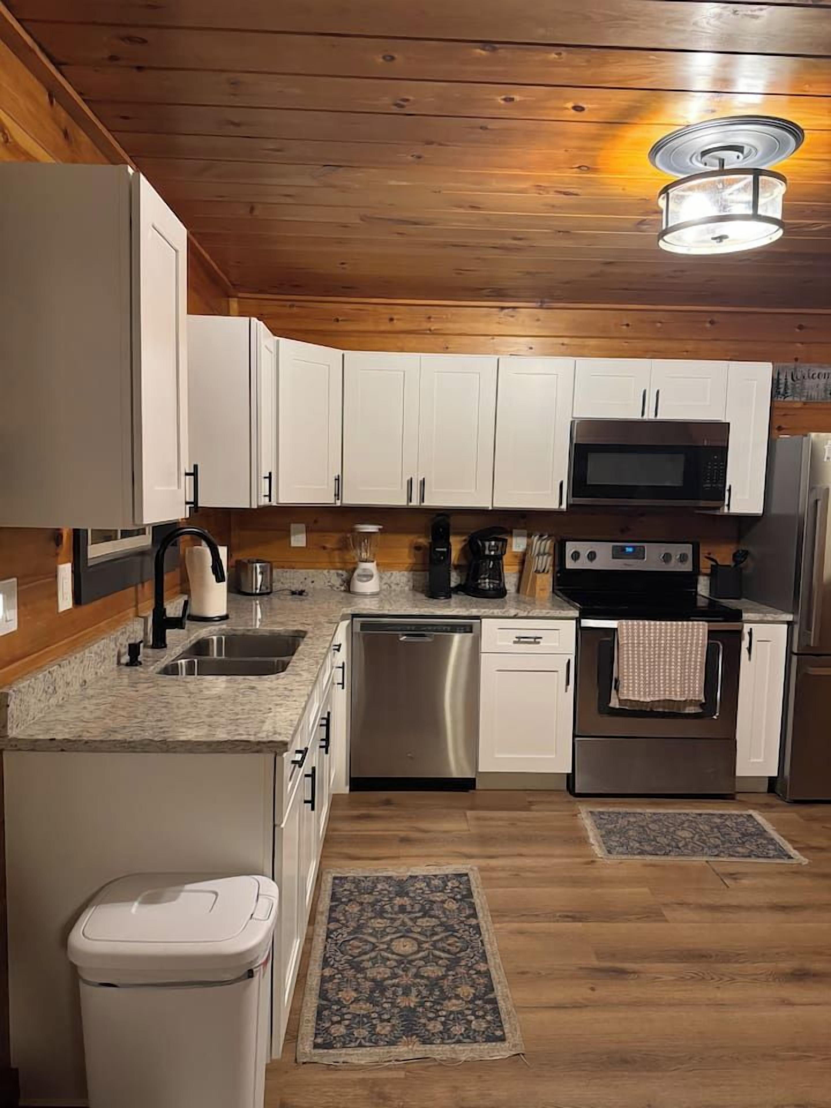 Una cocina moderna con armarios blancos, electrodomésticos de acero inoxidable y techo de madera.