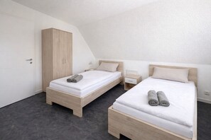 A bedroom with two beds, a wardrobe, and a nightstand. - Frankfurt airport family house (Mörfelden-Walldorf)