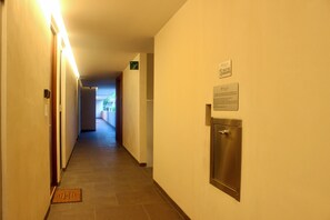 Ein Hotelgang mit einer Tür auf der rechten Seite, einem Schild darüber und Blick in einen weiteren Raum am Ende.