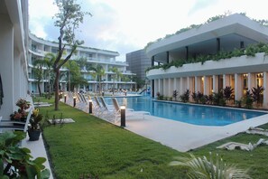 Ein modernes Hotel mit Pool, Liegestühlen und einem gepflegten Garten.